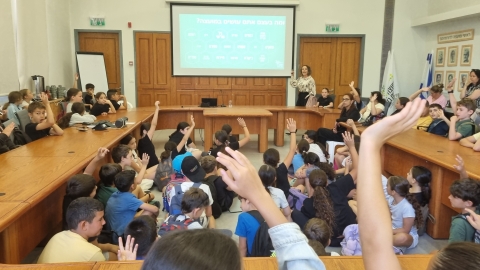 תלמידים מרימים יד כדי לשאול שאלות בשיחה עם ראשת המועצה רותם ידלין.jpg