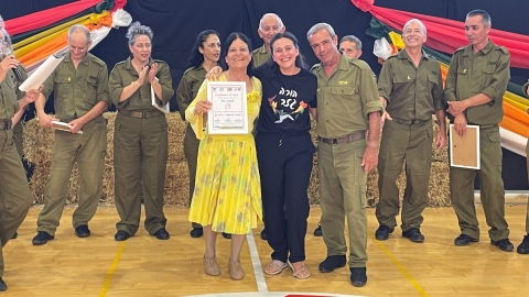 רקדנית מהורה גזר מצולמת עם קבוצה של חיילים אוחזת בתעודת השתתפות במופע לצהל באהבה.jpg