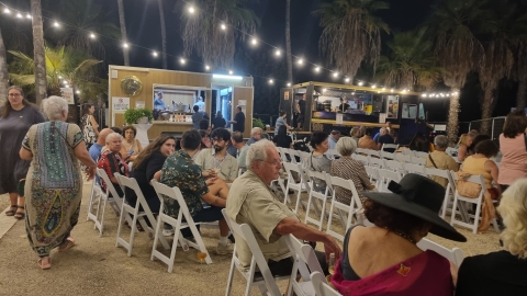אנשים יושבים במתחם סביב דוכן היין והפודטראק.jpg
