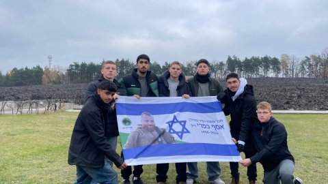 תלמידים מחזיקים דגל עם תמונתו של אסף כפרי זכרונו לברכה.jpeg