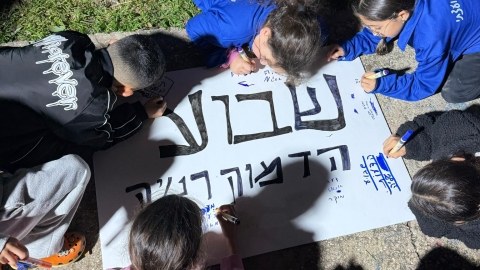 חניכים בתנועת נוער מכינים שלט.jpeg