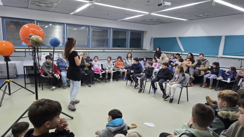 קבוצה יושבת בכיתה בה מסבירים על מערכת השמש באמצעות מודלים.jpeg