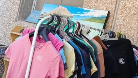 חולצות בית ספר צבעוניות יד שנייה תלויות על מעמד לתליית בגדים.jfif